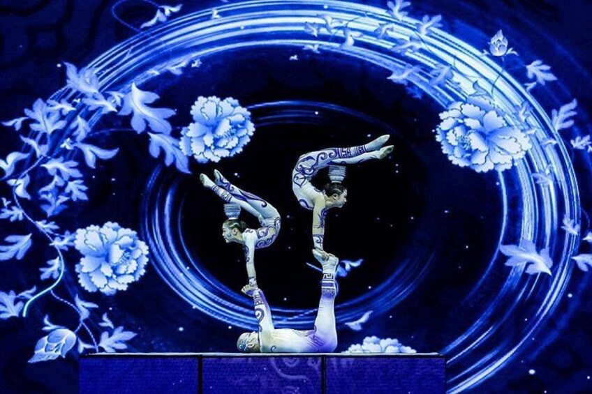 Une personne exécutant un numéro d’acrobatie avec une autre personne, le tout dans un décor composé de motifs floraux et de cercles. 1