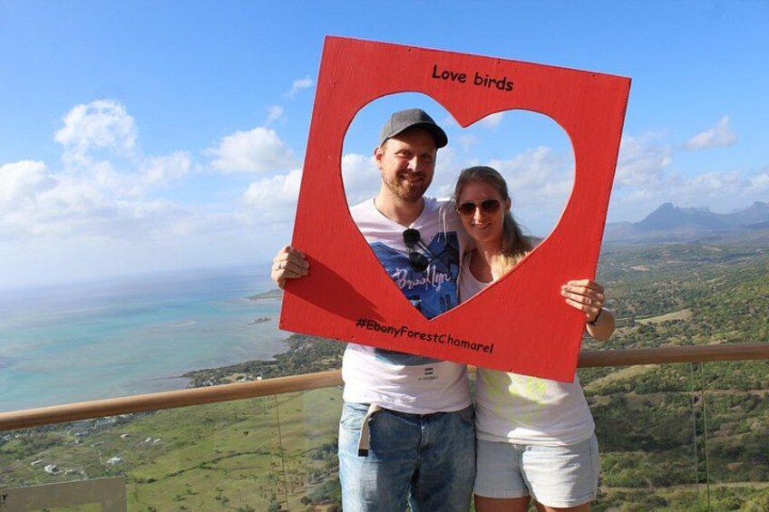 Un couple tenant une pancarte rouge en forme de cœur sur laquelle est écrit « Love birds » et un hashtag. 4