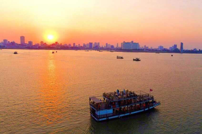 A sunset over a river with a boat in the foreground and a city skyline in the background. 3