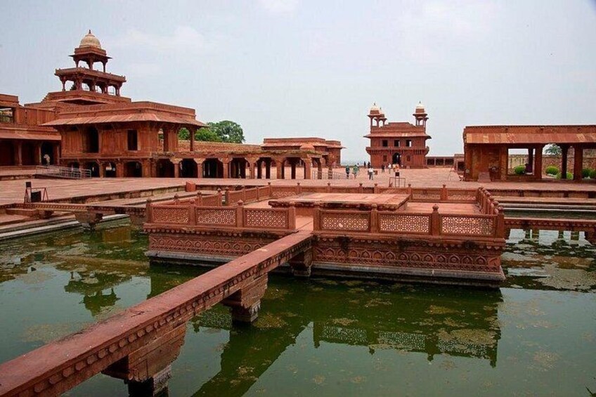 A historic building with intricate architecture, a bridge over water, and a reflection in the water. 4