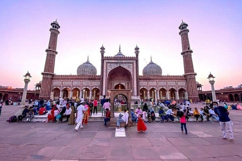 A large mosque with two minarets, a central dome, and a courtyard filled with people. 5