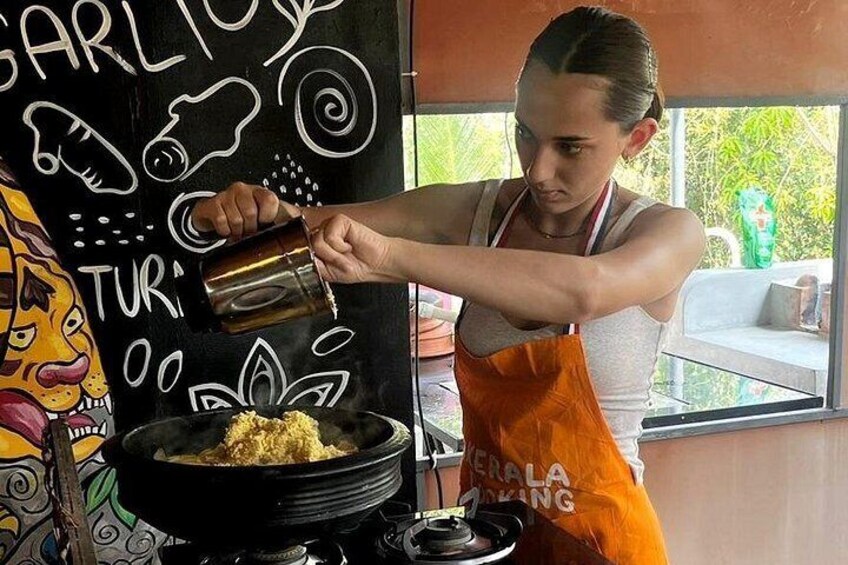 Une personne cuisine dans une cuisine. On y voit une casserole noire sur la cuisinière, une fenêtre et un mur orné de dessins. 5