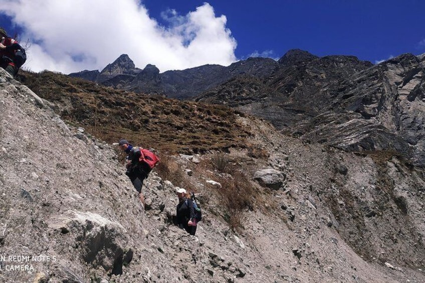 Hikers on a rocky mountain trail with a clear sky and distant mountains. 3