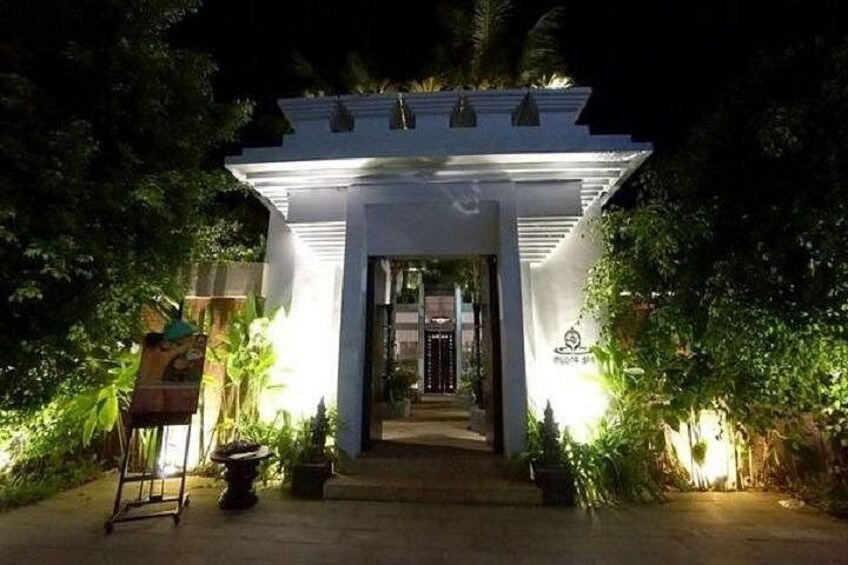 A white building with a covered entrance, surrounded by greenery. 2