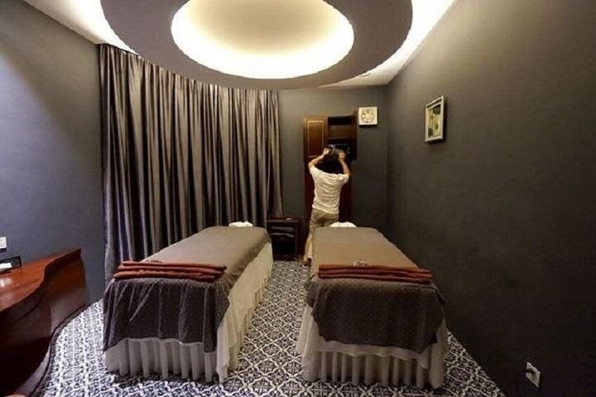 A room with two beds, a large window with curtains, a wooden desk, and a person standing by the window. 3