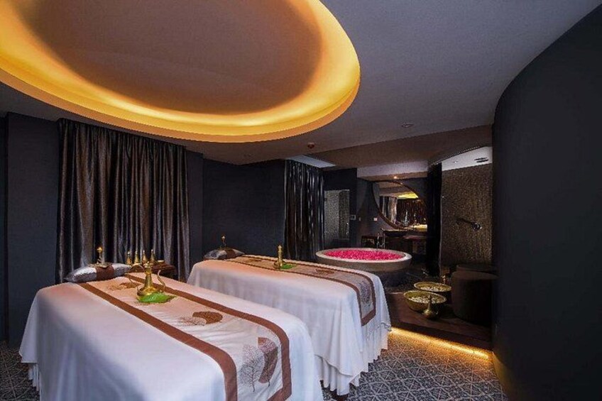 A spa room with two massage tables, a decorative fountain, and a modern ceiling light fixture. 1