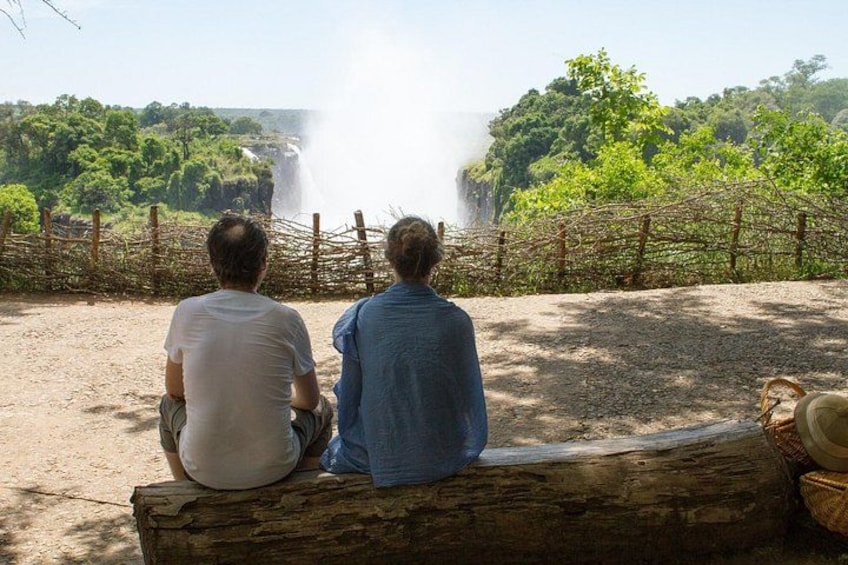 Two people sitting on a bench overlooking a waterfall. 4