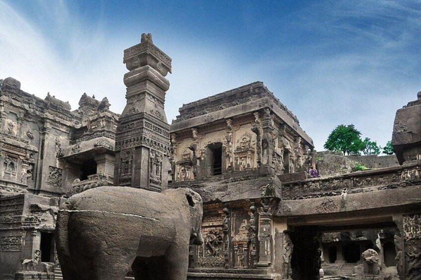 Ancient stone architecture with intricate carvings and a large rock formation. 5