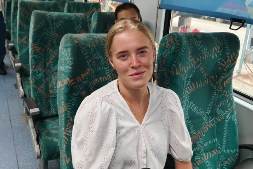 Una persona sentada en un autobús con asientos de estampado verde. 3