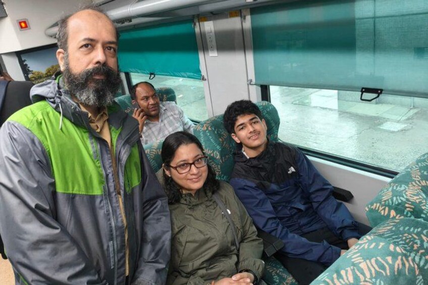 Un grupo de personas sentadas en un tren con tapicería estampada. 2