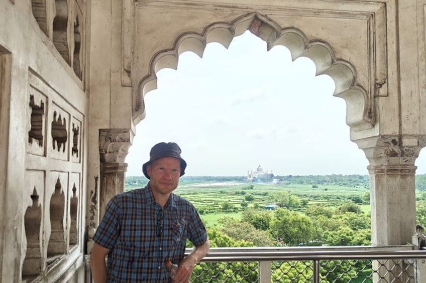 Un hombre está de pie frente a un edificio histórico con vistas a un monumento lejano. 2