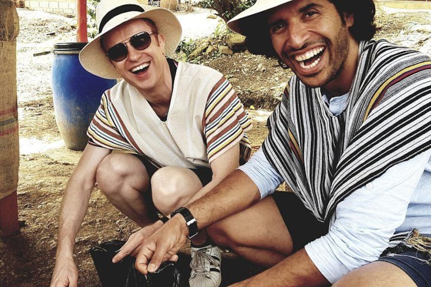 Two people sitting outdoors, one wearing a striped shirt and a hat, and the other in a striped shirt and shorts. 3