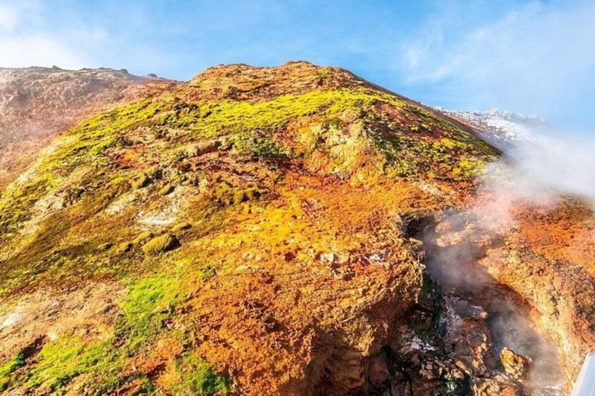Una montaña con una chimenea de vapor, terreno rocoso y vegetación escasa. 2
