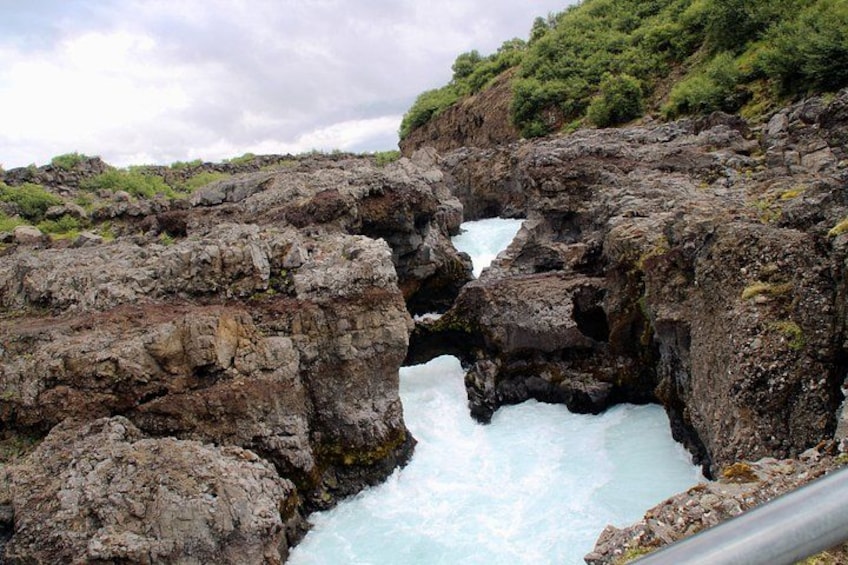 Un paisaje costero rocoso con una cascada que fluye a través de un arco natural. 5