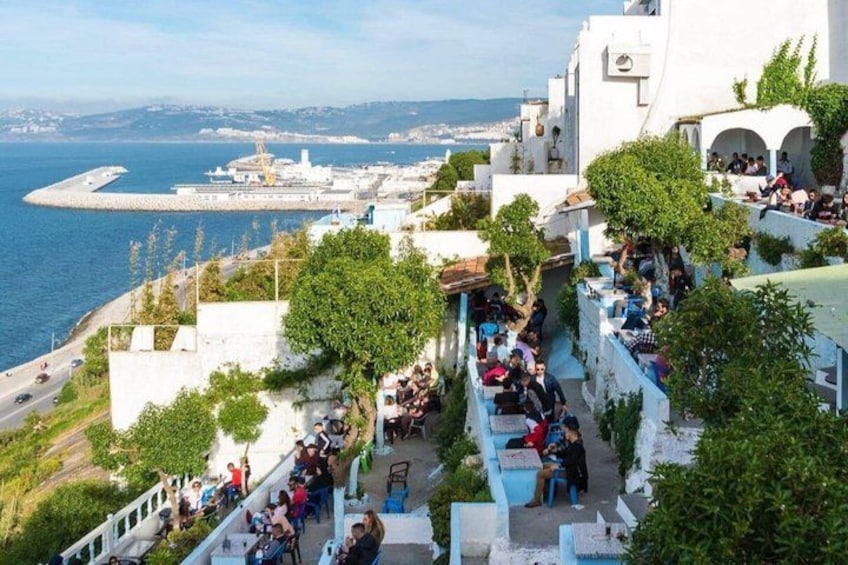 A coastal town with people sitting on balconies overlooking the sea. 4