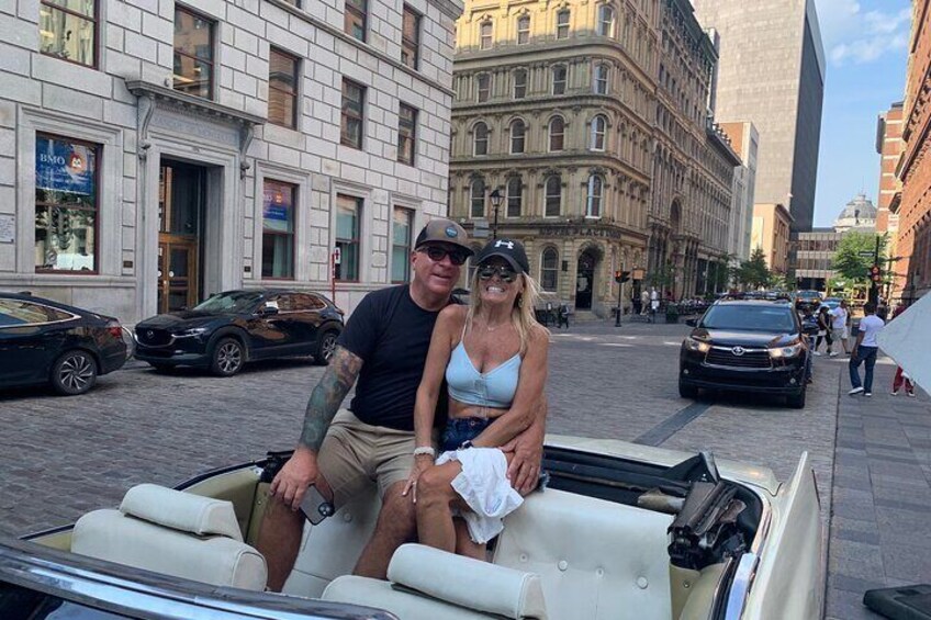 A convertible car parked on a city street with buildings in the background. 3