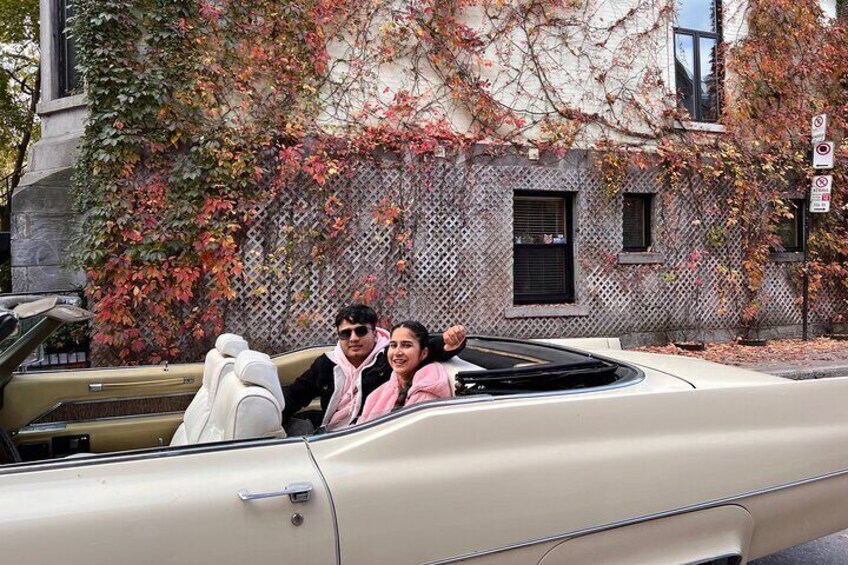 A vintage convertible car parked on a street with autumn foliage. 2