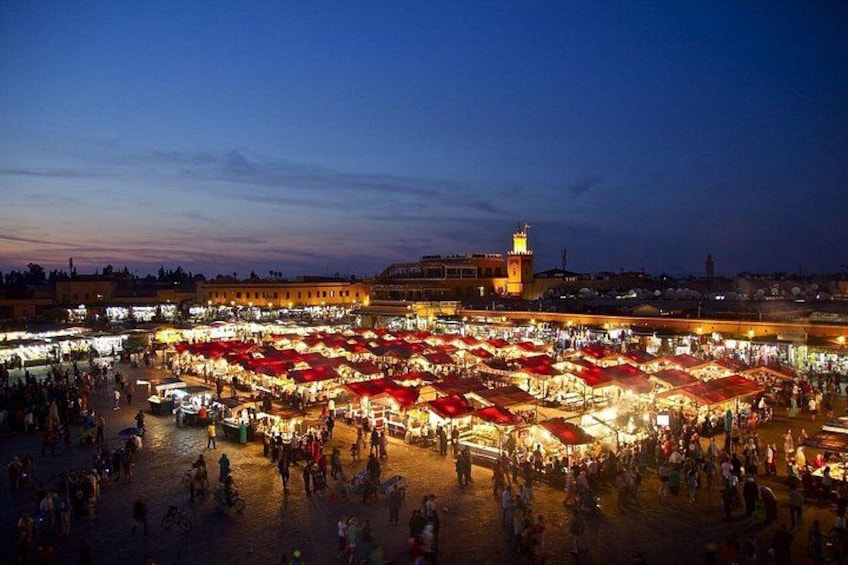 Een levendige markt in de open lucht bij zonsondergang, met talloze kraampjes en mensen. 2