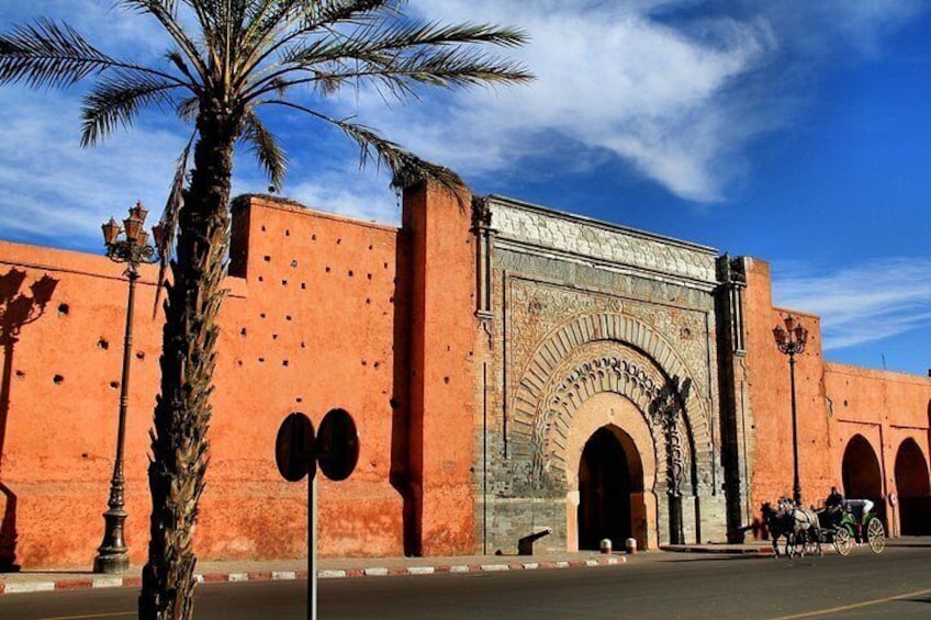 A historic building with a large archway, palm trees, and a clear blue sky. 4