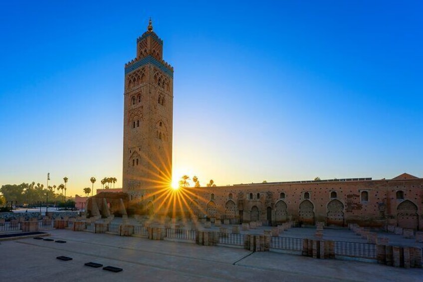 A historic tower with arches, a clear sky, and the sun setting in the background. 2