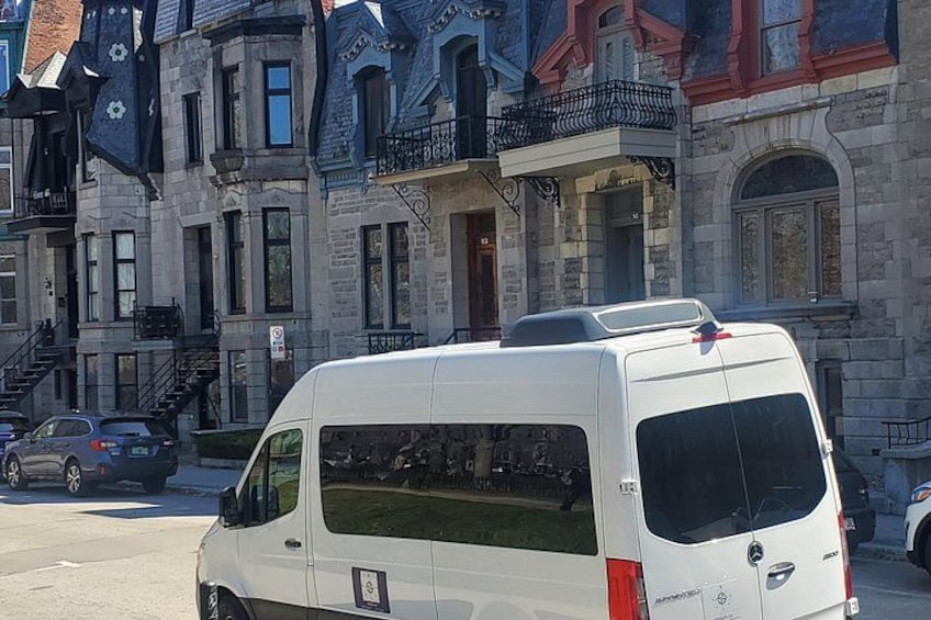 Una camioneta blanca estacionada en una calle con edificios históricos al fondo. 1