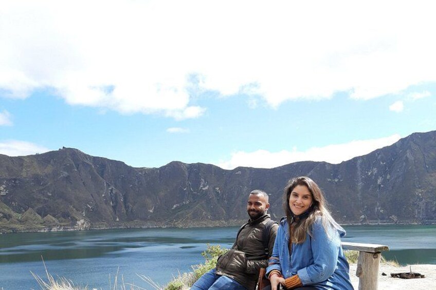 Two people sitting by a lake with mountains in the background. 4