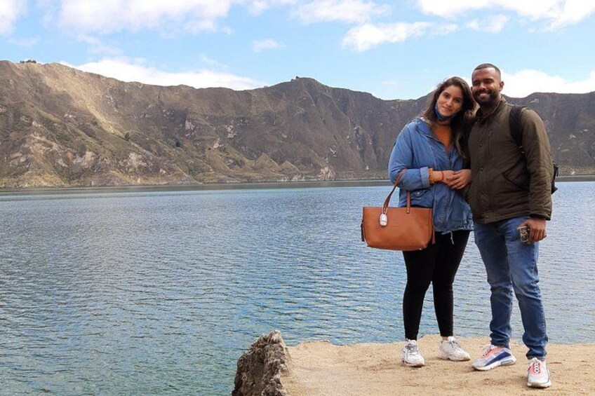 A couple standing by a lake with mountains in the background. 3