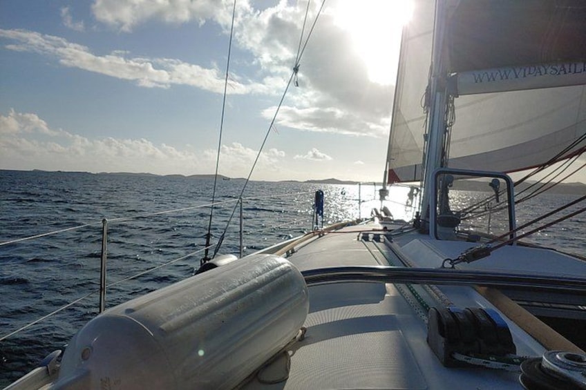 En segelbåt på vattnet med en person som står vid aktern. 1