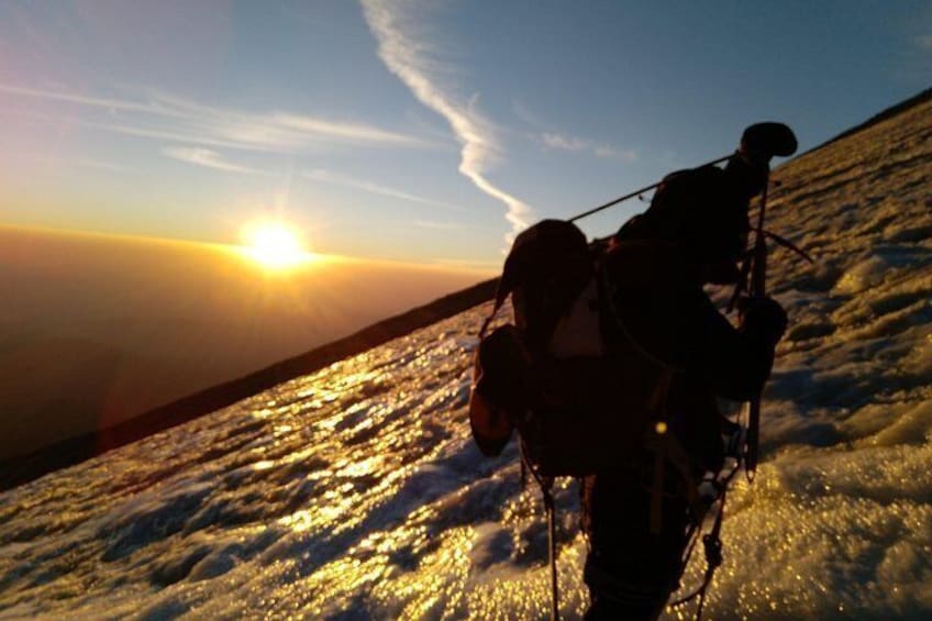 A person hiking with a backpack on a snowy mountain during sunset. 2