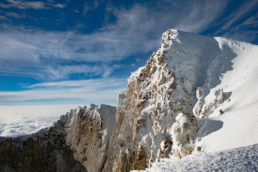 A snow-covered mountain peak with rugged terrain and a clear sky. 1