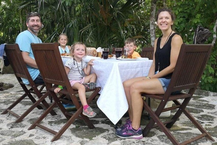 En familie spiser udendørs ved et bord med stole. 4
