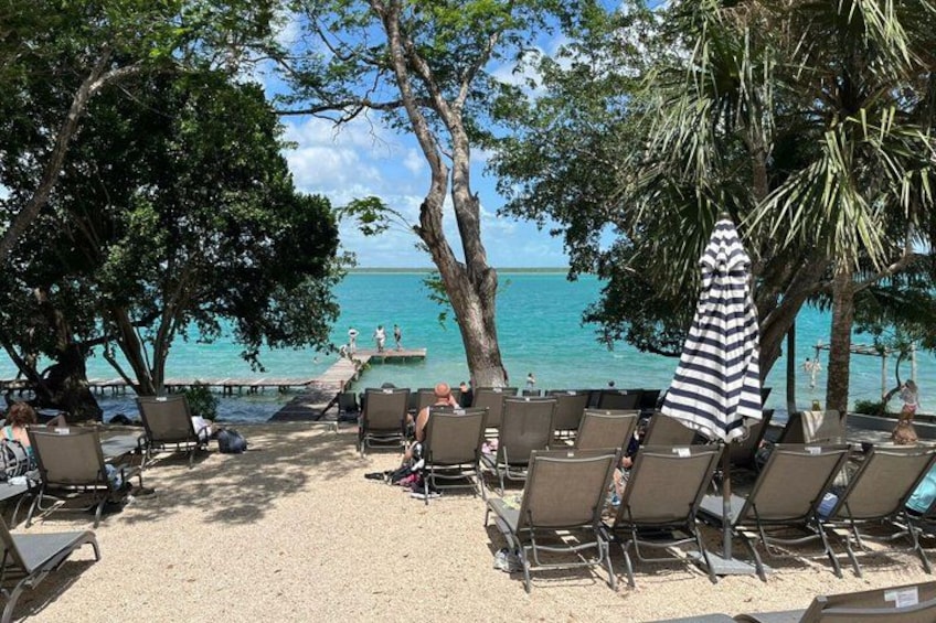A beach with lounge chairs and umbrellas, a pier extending into the water, and a clear view of the ocean. 3