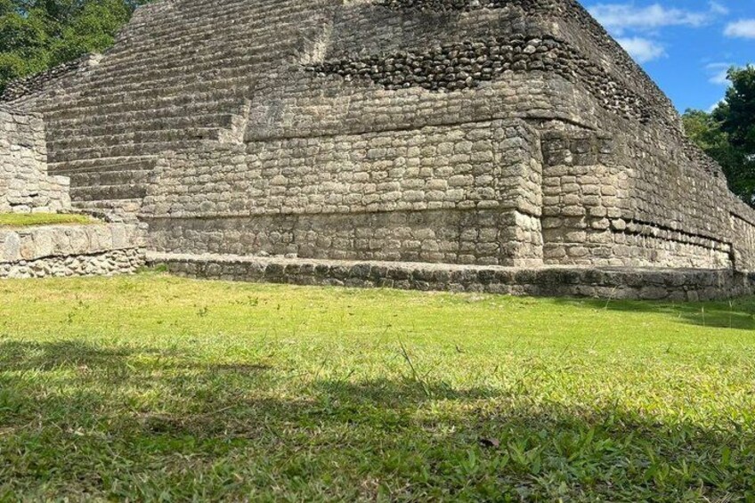 Una gran estructura piramidal de piedra con un primer plano cubierto de césped. 2