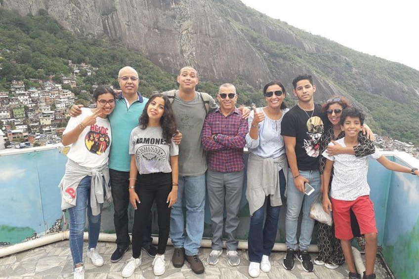 A group of people posing on a rooftop with a mountainous landscape in the background. 1