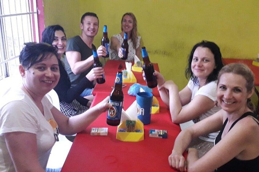 A group of people sitting around a red table with bottles and a blue cup. 4