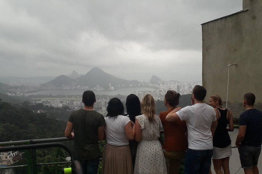 A group of people standing on a balcony overlooking a cityscape with mountains in the background. 2