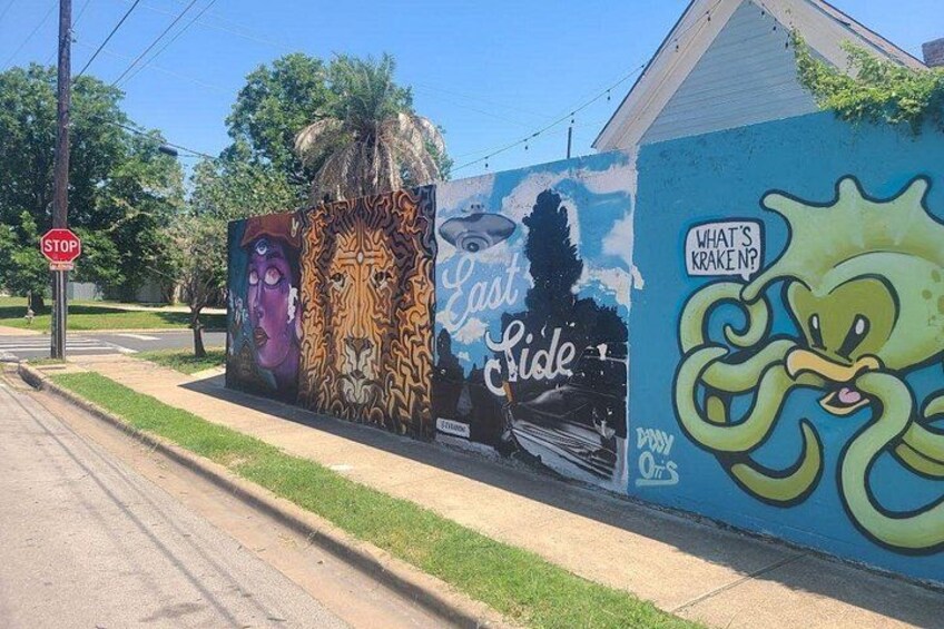 A mural with a lion, a woman, and a green octopus on a wall. 3