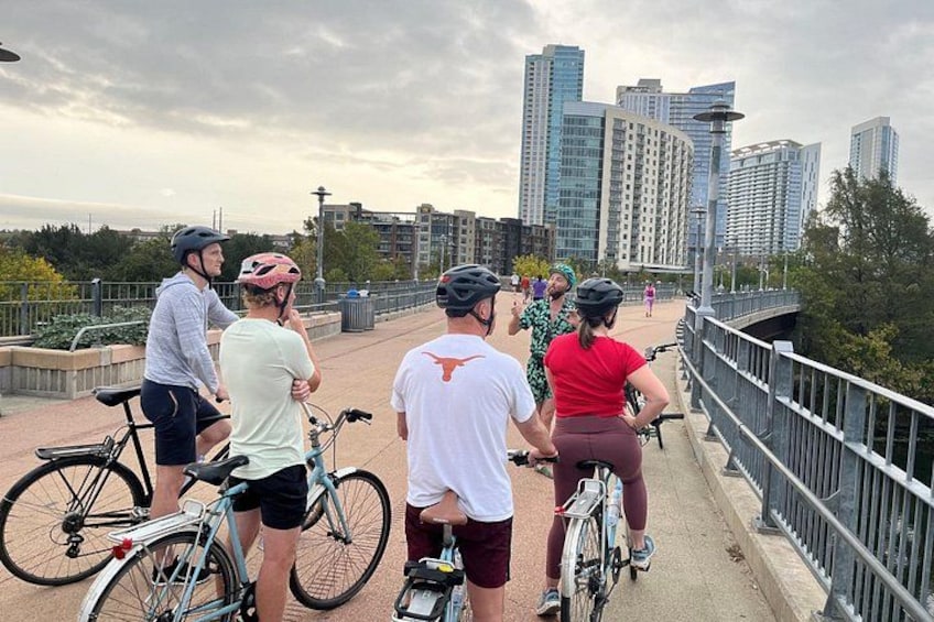 A group of cyclists on a bridge with a city skyline in the background. 2
