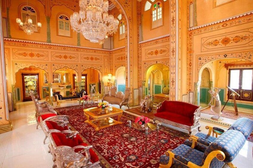 An opulent room with ornate decorations, a red sofa, and a patterned carpet. 4