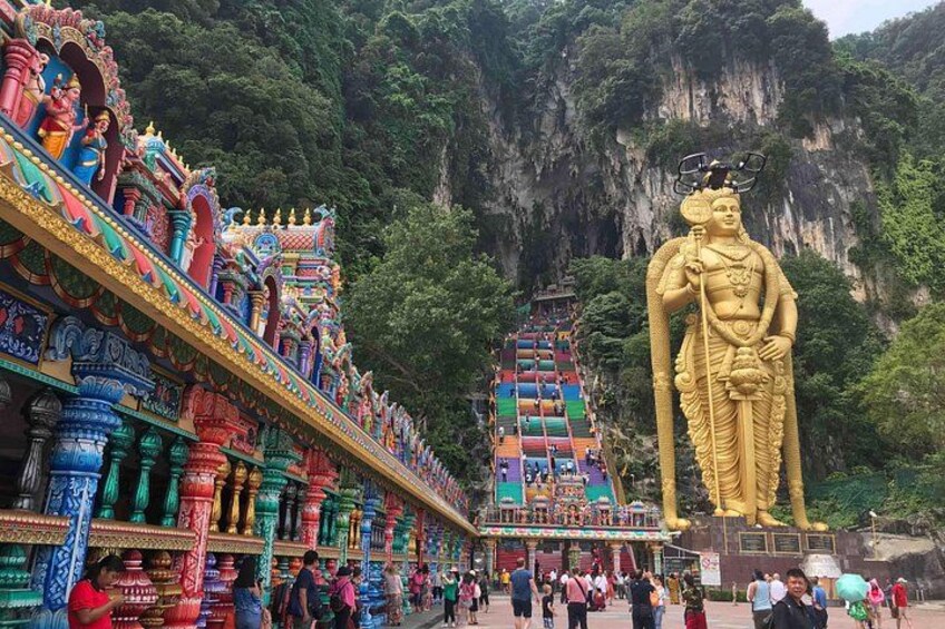 A large golden statue, colorful temple architecture, and a mountainous backdrop. 5