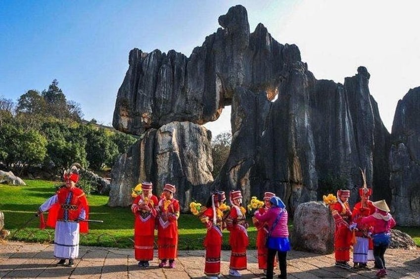 A group of people in traditional costumes performing in front of a rock formation. 5