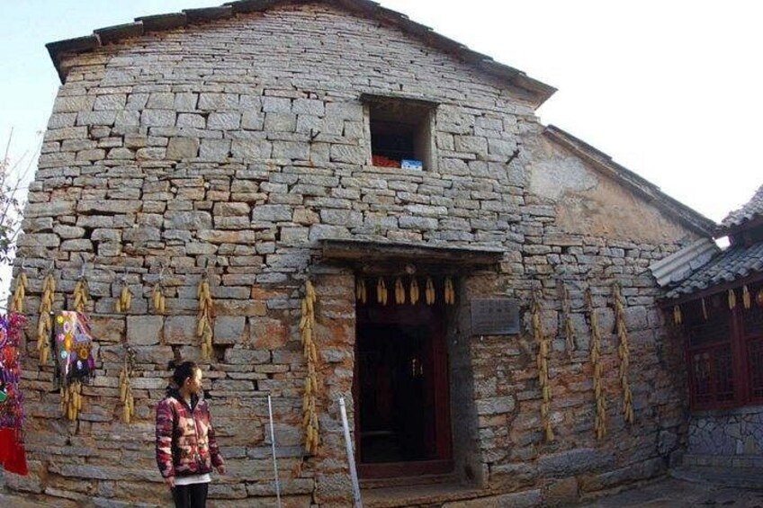 A stone building with a traditional design, a small window, and hanging items on the wall. 2