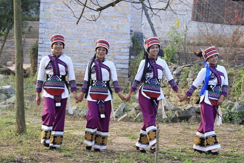 Three individuals in traditional attire walking on a path. 3