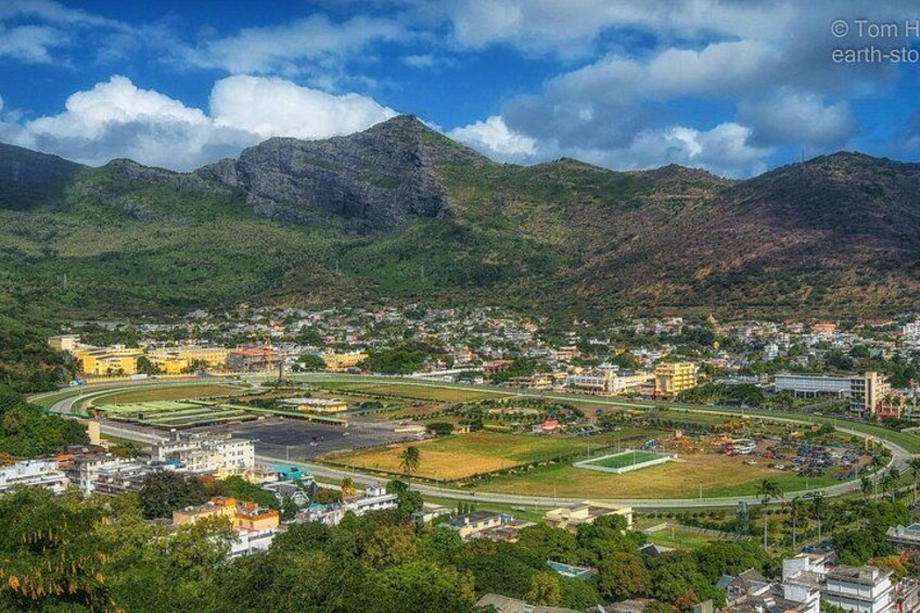 Un pueblo con una pista de carreras, edificios y montañas al fondo. 3