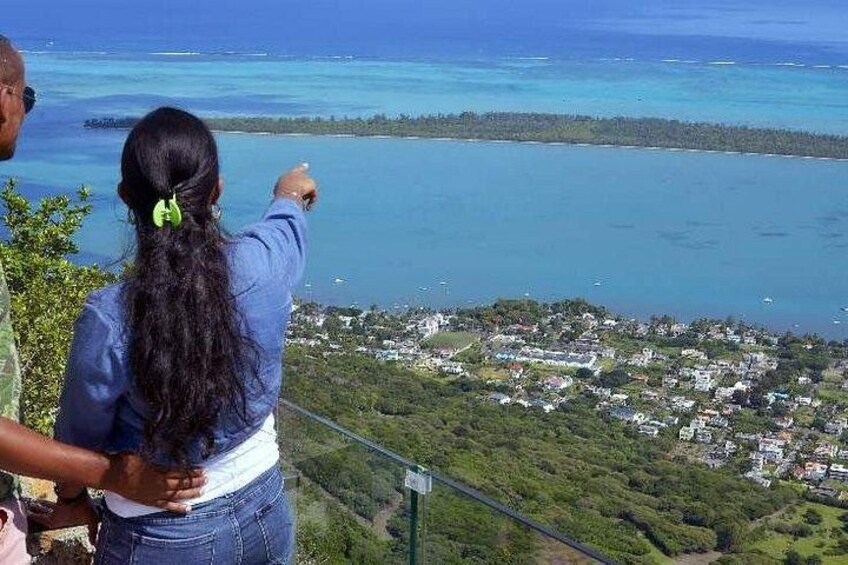 A person pointing at a coastal landscape with a view of the ocean and a town below. 2