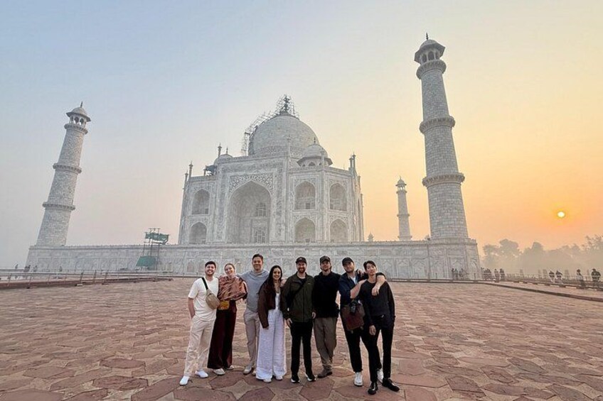 Un groupe de personnes se tient devant le Taj Mahal, dont on peut voir les minarets et le dôme. 5