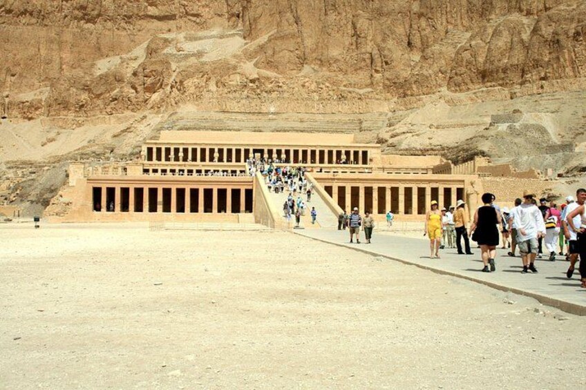 A large ancient Egyptian temple with a long staircase leading up to it, surrounded by desert. 1