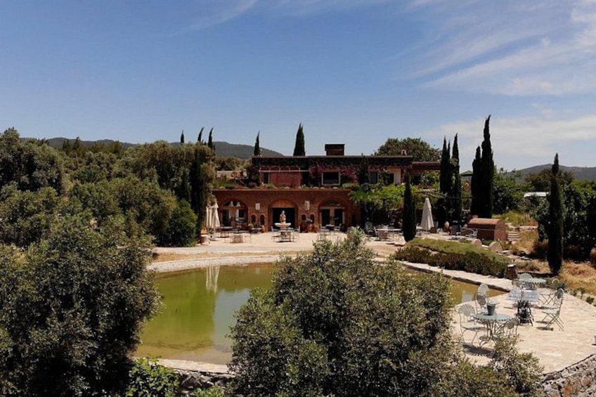A historic building with a courtyard, a pond, and surrounding trees. 1