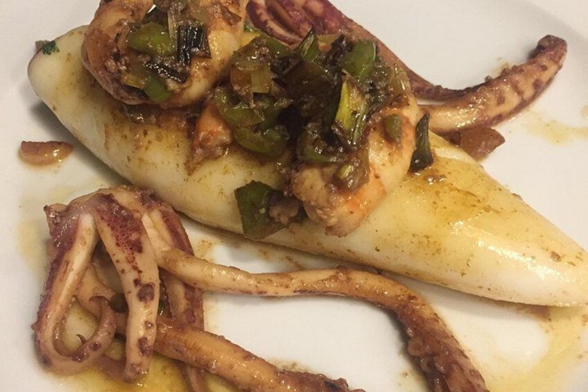 A dish of octopus with green peppers and a sauce. 3