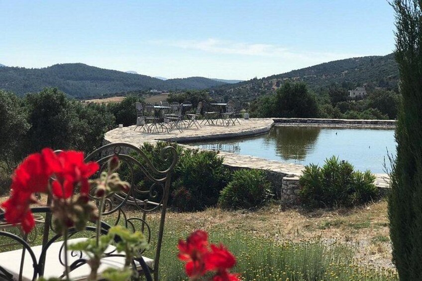 A lakeside patio with outdoor furniture, surrounded by greenery and hills. 2